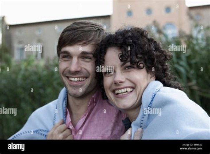 Laughing couple wrapped in a blanket